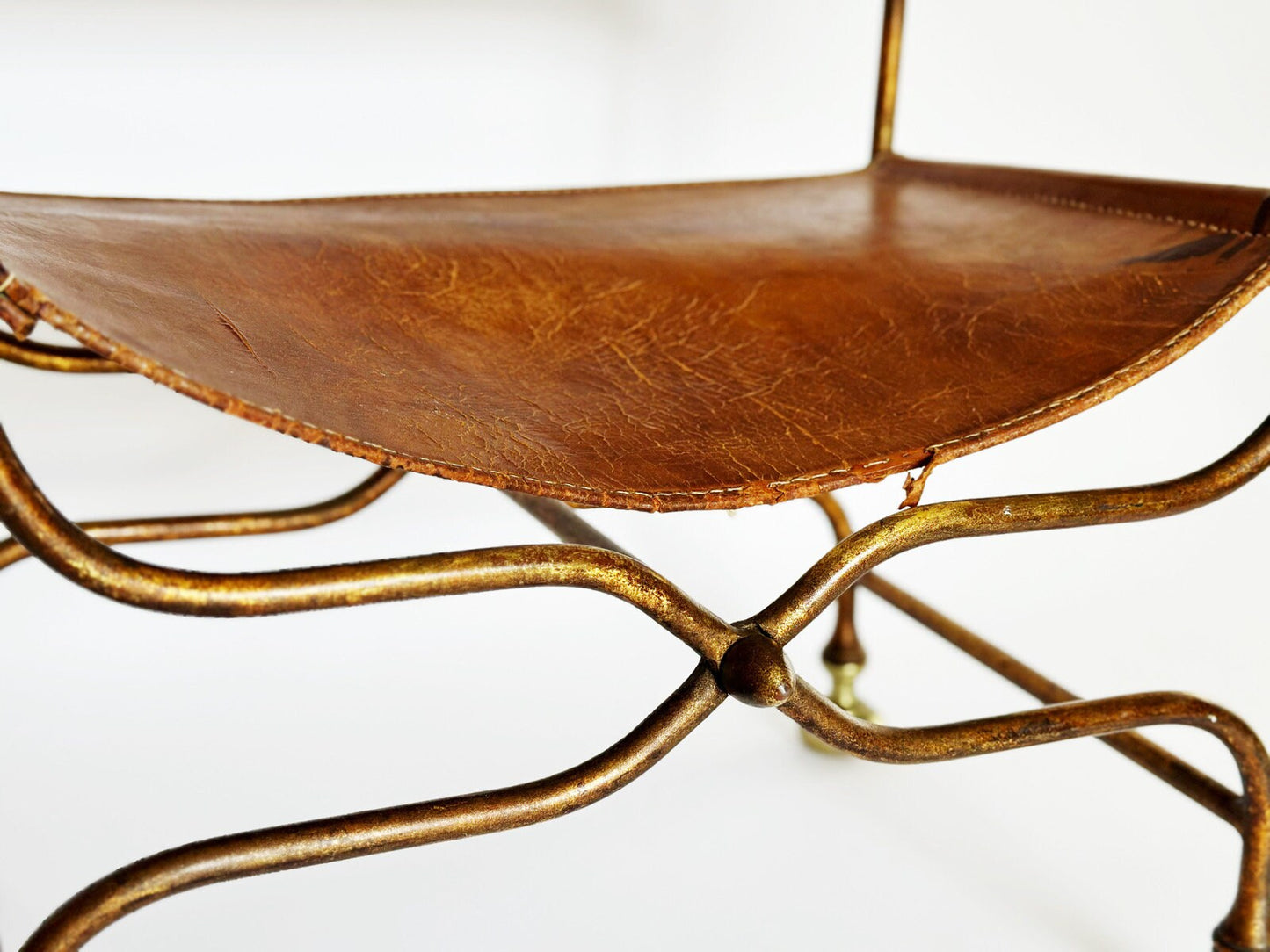 The base of the antique Italian Savonarola chair feature a unique iron X design on the front and back of the chair in a copper color finish. The seat is a rich brown distressed leather.