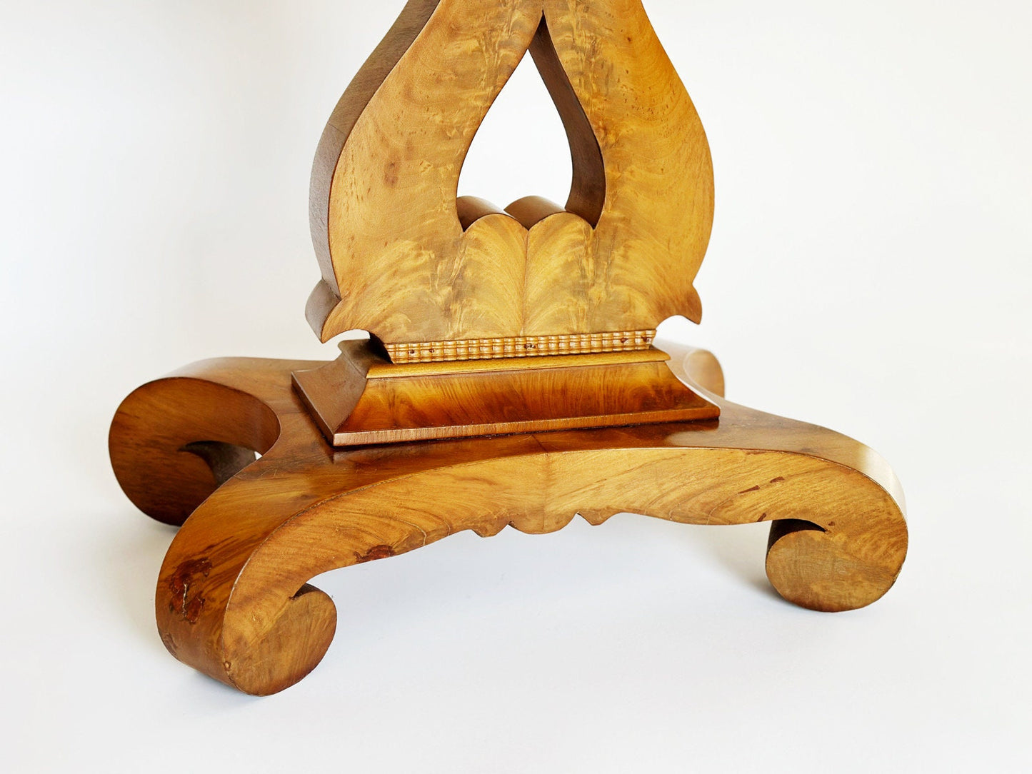 The vintage antique Empire game and end table is made from burl wood and has a beautiful harp shape design of the pedestal base. The burl provides lots of warmth and texture. There are 4 feet at the base of the pedestal that curl under.