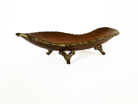 Copper dish with three ornate gold feet.